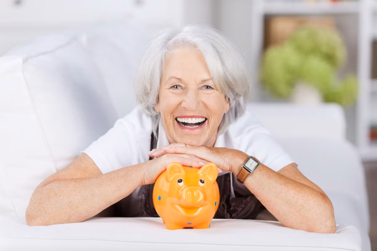 Lachende Seniorin mit ihrem Sparschwein